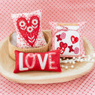 Decorative pillows with heart and 'LOVE' designs on a pink checkered background