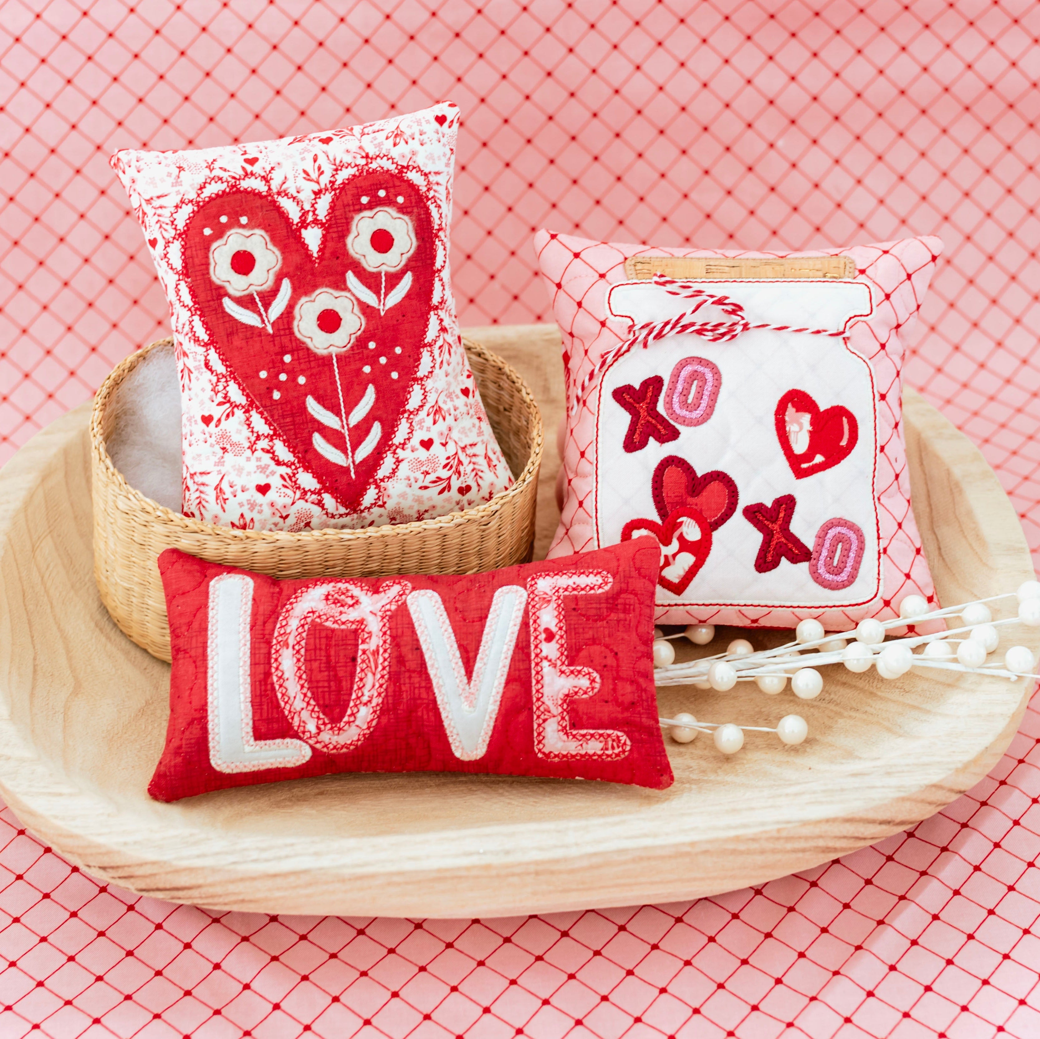Decorative pillows with heart and 'LOVE' designs on a pink checkered background