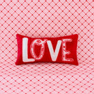 Red pillow with 'LOVE' text on a pink textured background