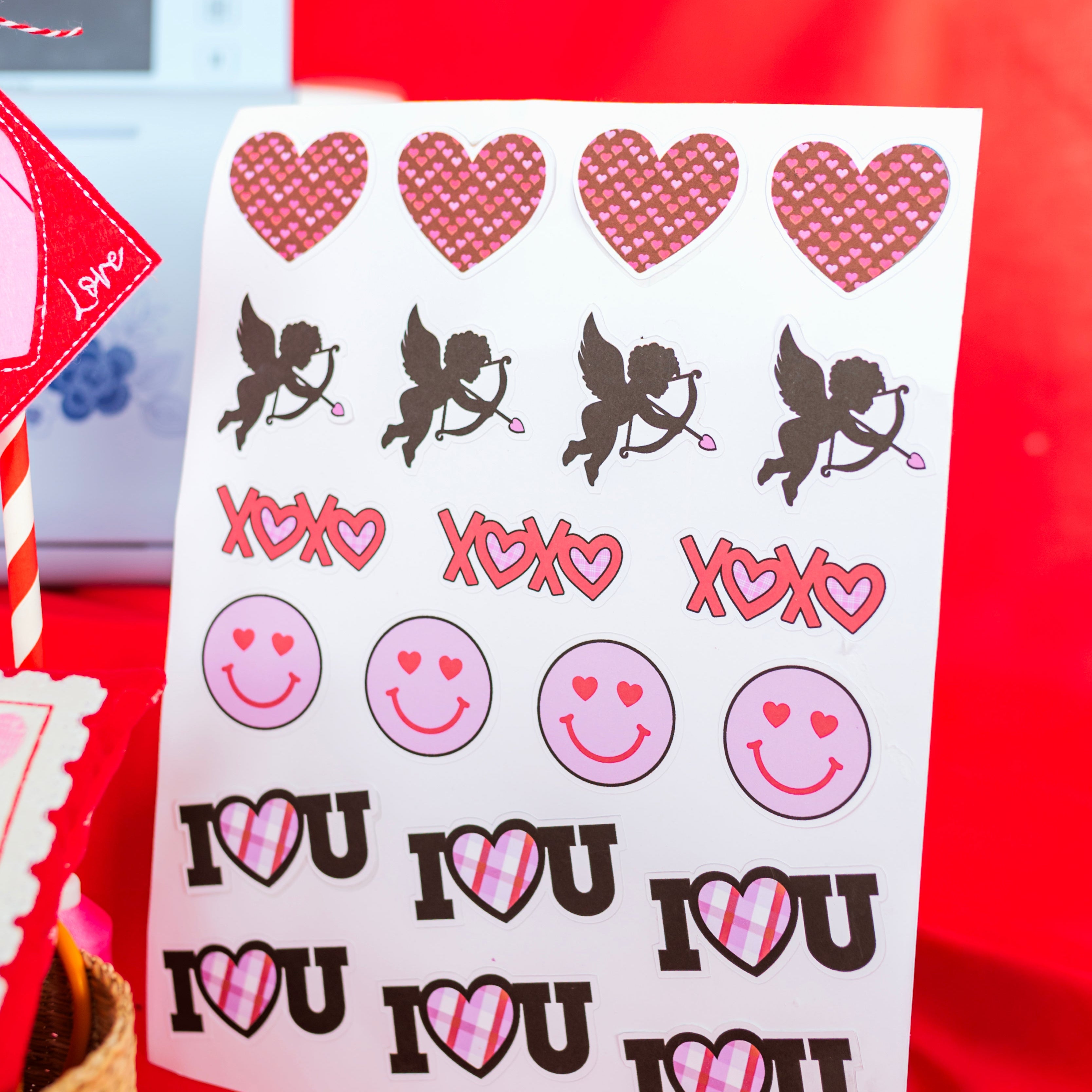 Sheet of stickers with hearts, cupids, and 'I LOVE YOU' text on a red background.
