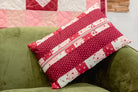 Red and white patterned pillow with a zipper on a green couch