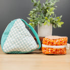 Two handmade fabric pouches displayed on a light wood tabletop against a dark gray background. The larger pouch on the left is made of mint green and white patterned fabric with a mint green strap.