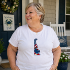 Woman wearing a white t-shirt with a graphic design on a porch.