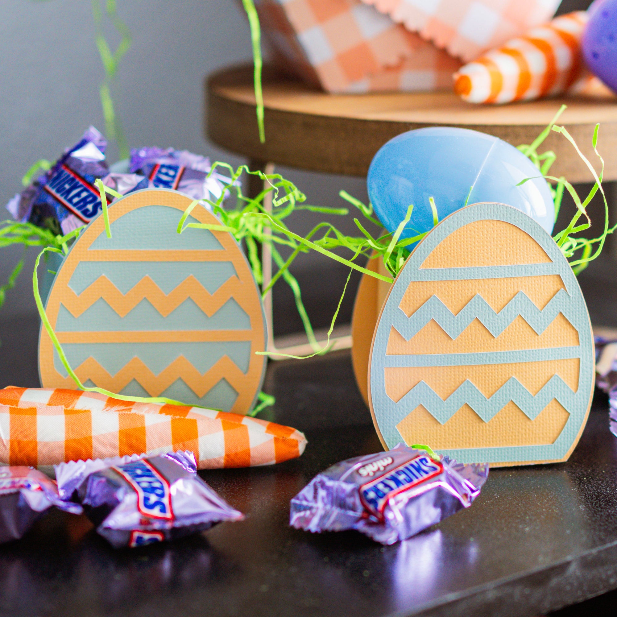 Decorative Easter egg-shaped candies with candy bars on a dark surface.