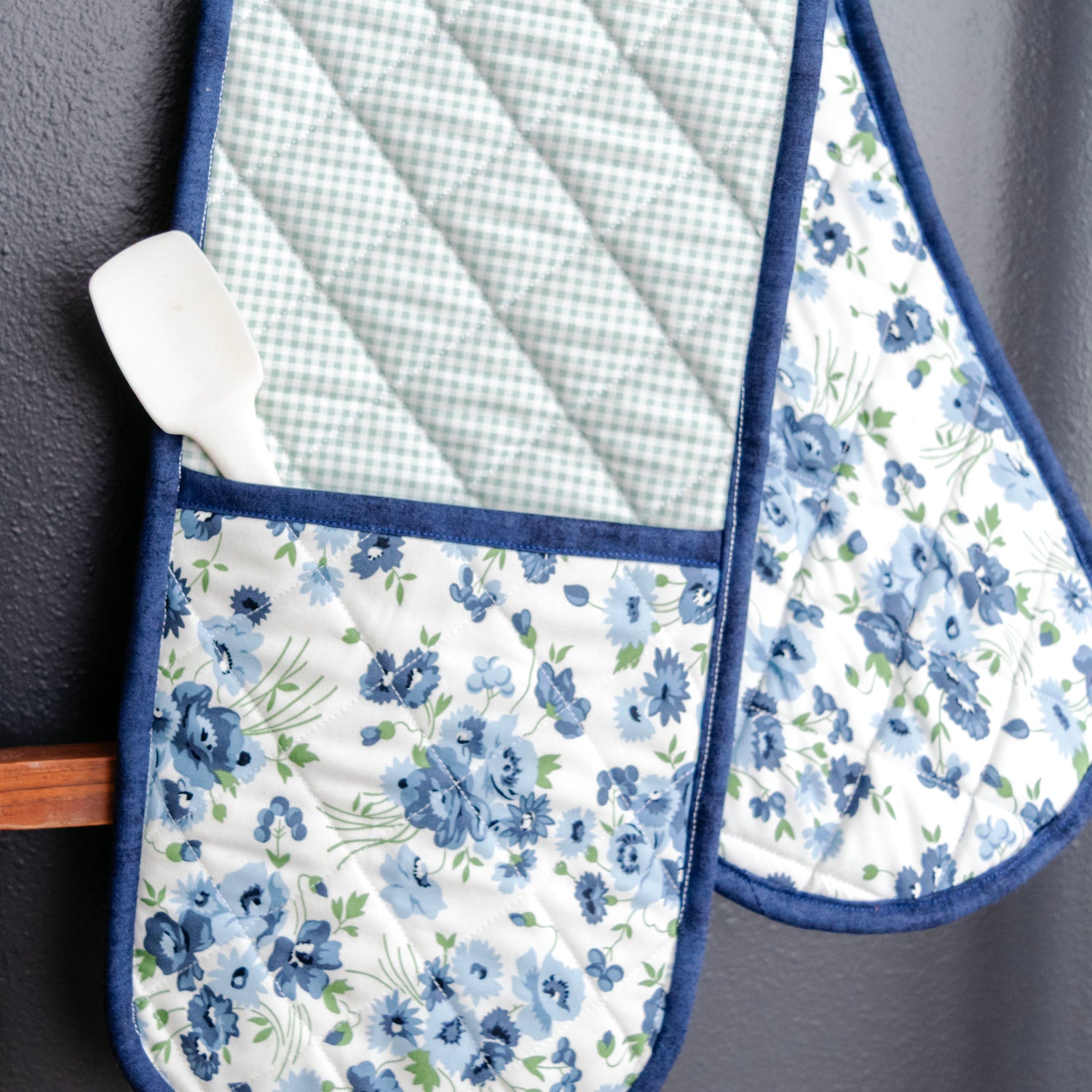 Set of floral oven mitts and pot holders on a dark surface
