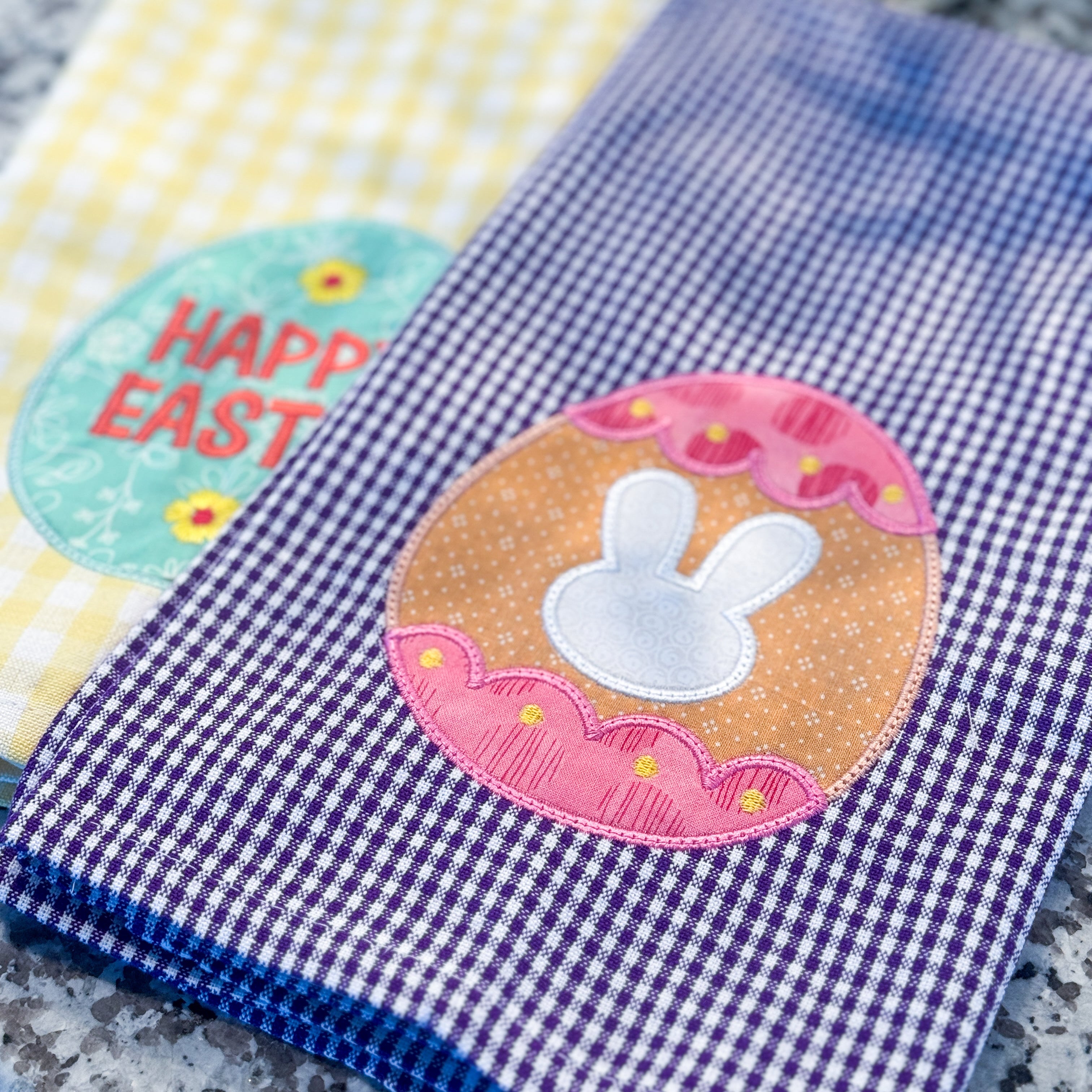 Two embroidered towels with decorative patches on a textured surface