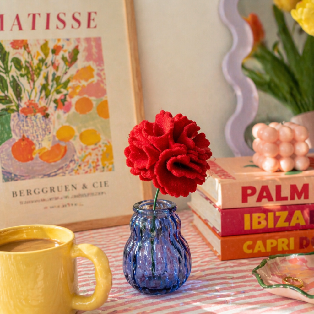 Colorful still life with a mug, flowers, books, and a painting of Matisse.