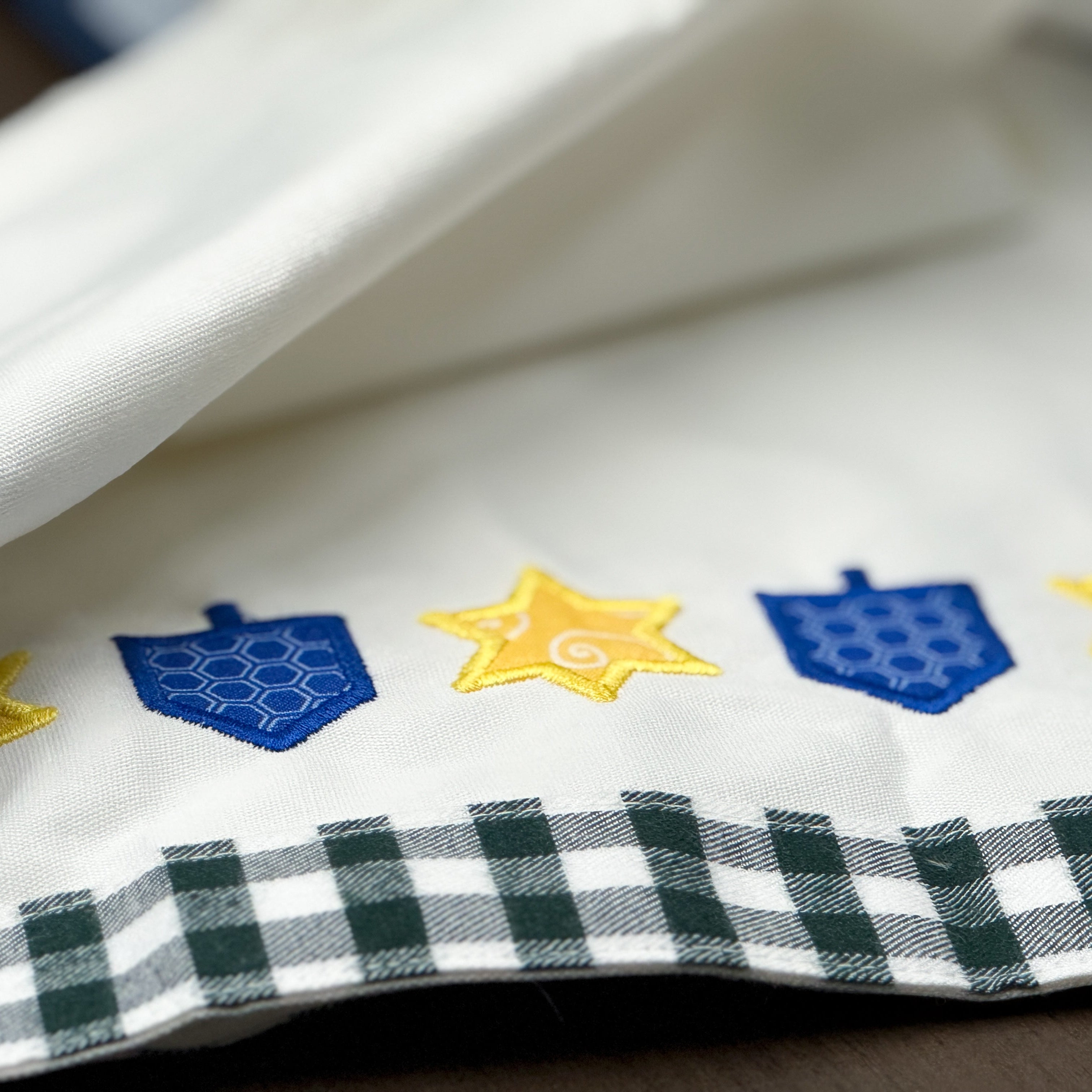 Close-up of a fabric with embroidered symbols including stars and hexagons on a checkered border.