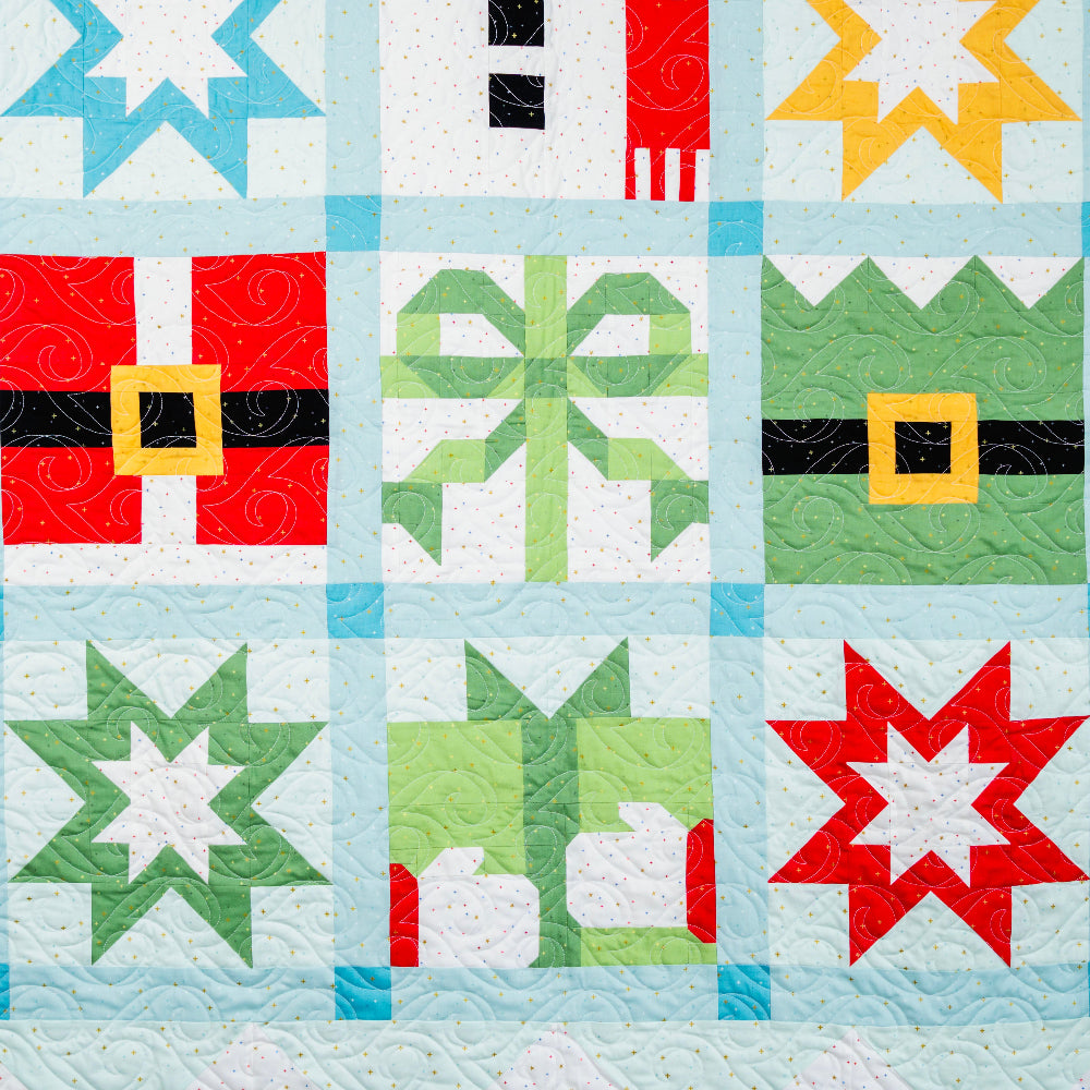 Quilt with star and block patterns in red, green, blue, and yellow on a light blue background.