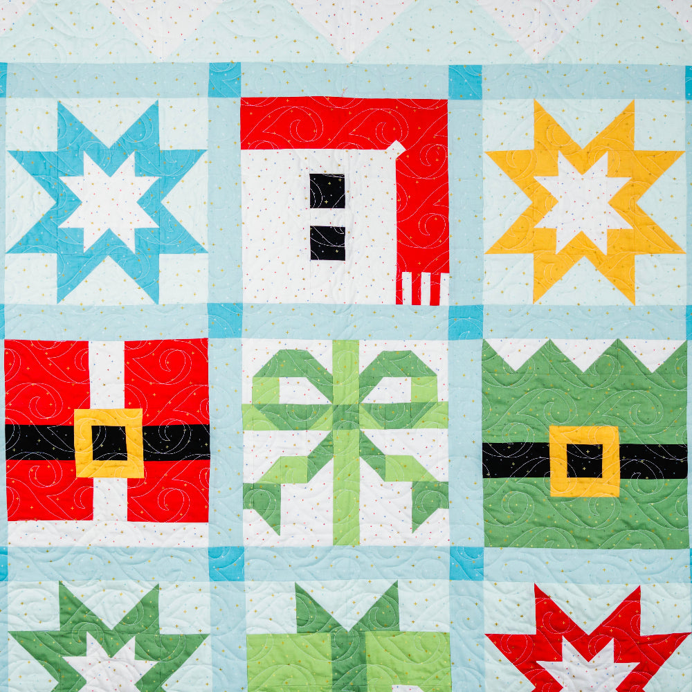 Quilt block with festive patterns including stars, a house, and a bow tie on a light blue background.