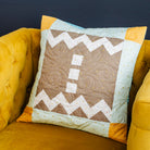 Decorative pillow with zigzag pattern on a yellow armchair against a dark blue wall