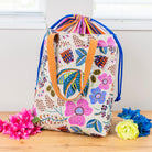 Floral-patterned drawstring bag with a handle on a wooden surface with flowers.