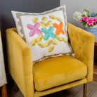 Yellow armchair with a colorful butterfly-patterned pillow against a gray wall.