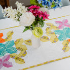 Colorful floral arrangement in a vase on a table with a patchwork tablecloth.