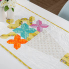 Colorful quilted table runner with star patterns on a white surface.