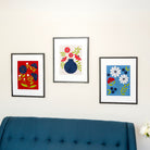 Three framed artworks on a wall above a blue sofa