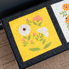 Two floral quilt blocks on a wooden surface