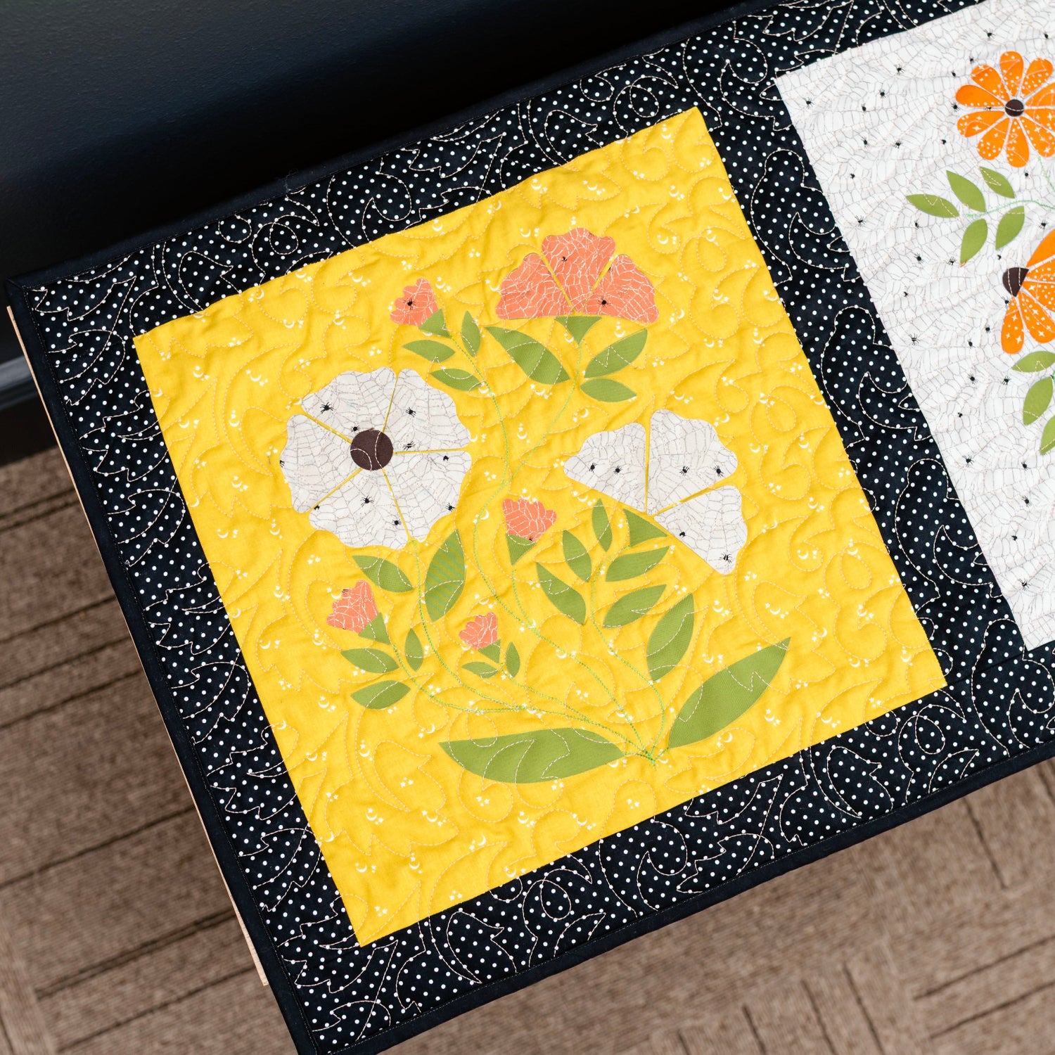 Two floral quilt blocks on a wooden surface