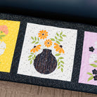 Three floral quilt blocks on a dark surface