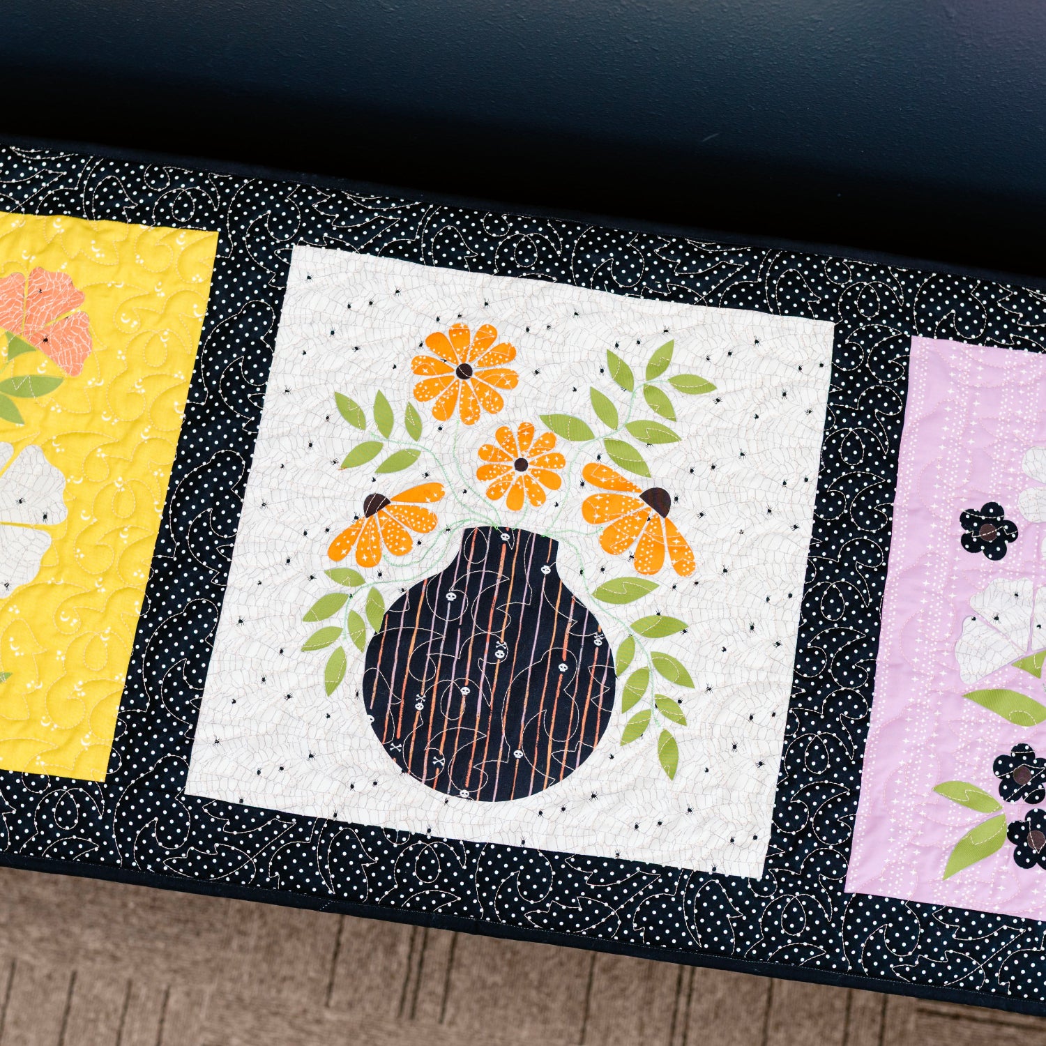 Three floral quilt blocks on a dark surface