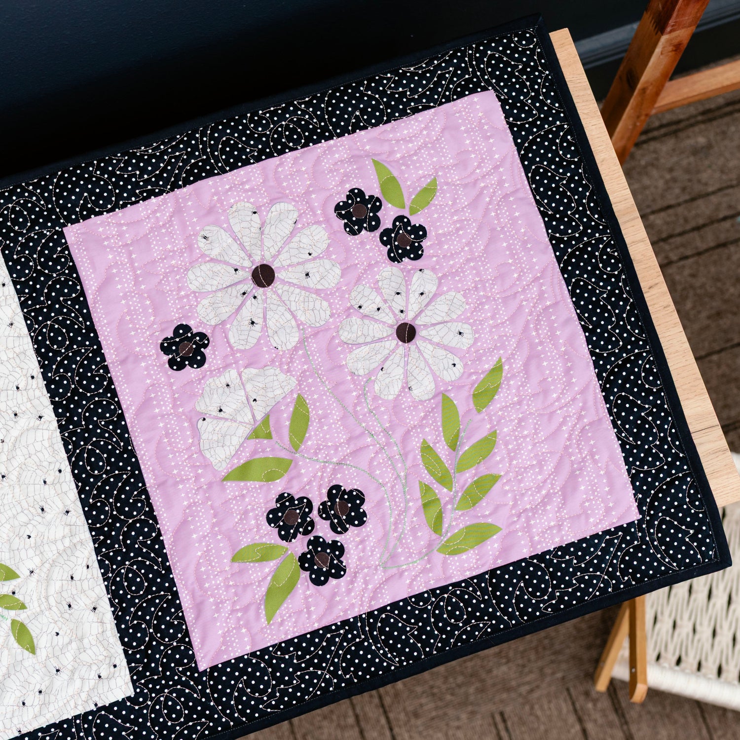 Two quilted blocks with floral designs on a wooden surface.