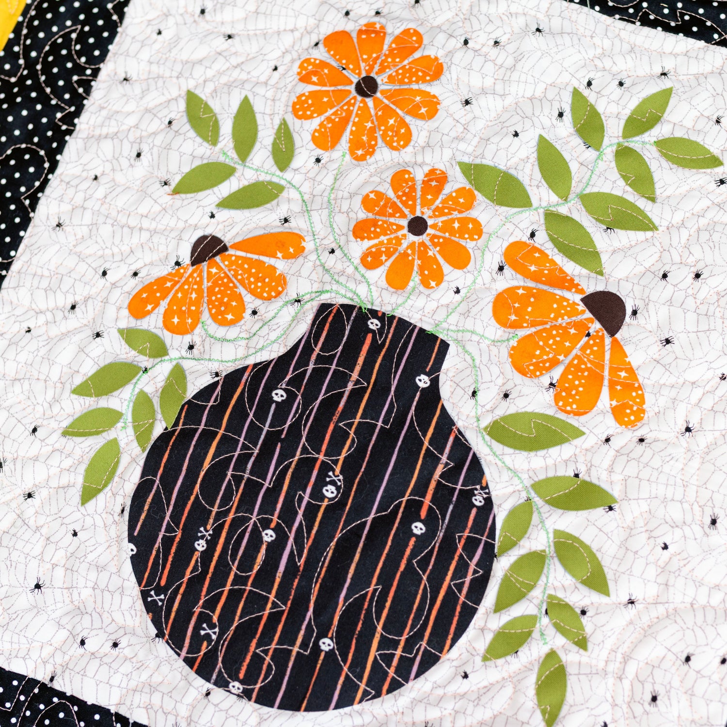 Quilt block with a black vase and orange flowers on a white background