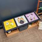 Three colorful quilted panels on a wooden bench against a dark wall.