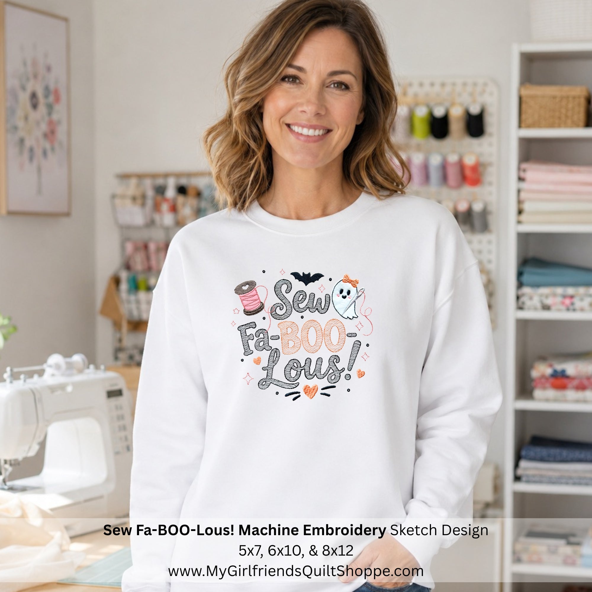 A smiling woman stands in a sewing room wearing a white crewneck sweatshirt with a colorful graphic that reads 'Sew Fa-BOO-Lous!' with a spool of thread, ghost, bat, and pumpkin details. A sewing machine is visible on the left, and shelves of fabrics and thread are in the background.