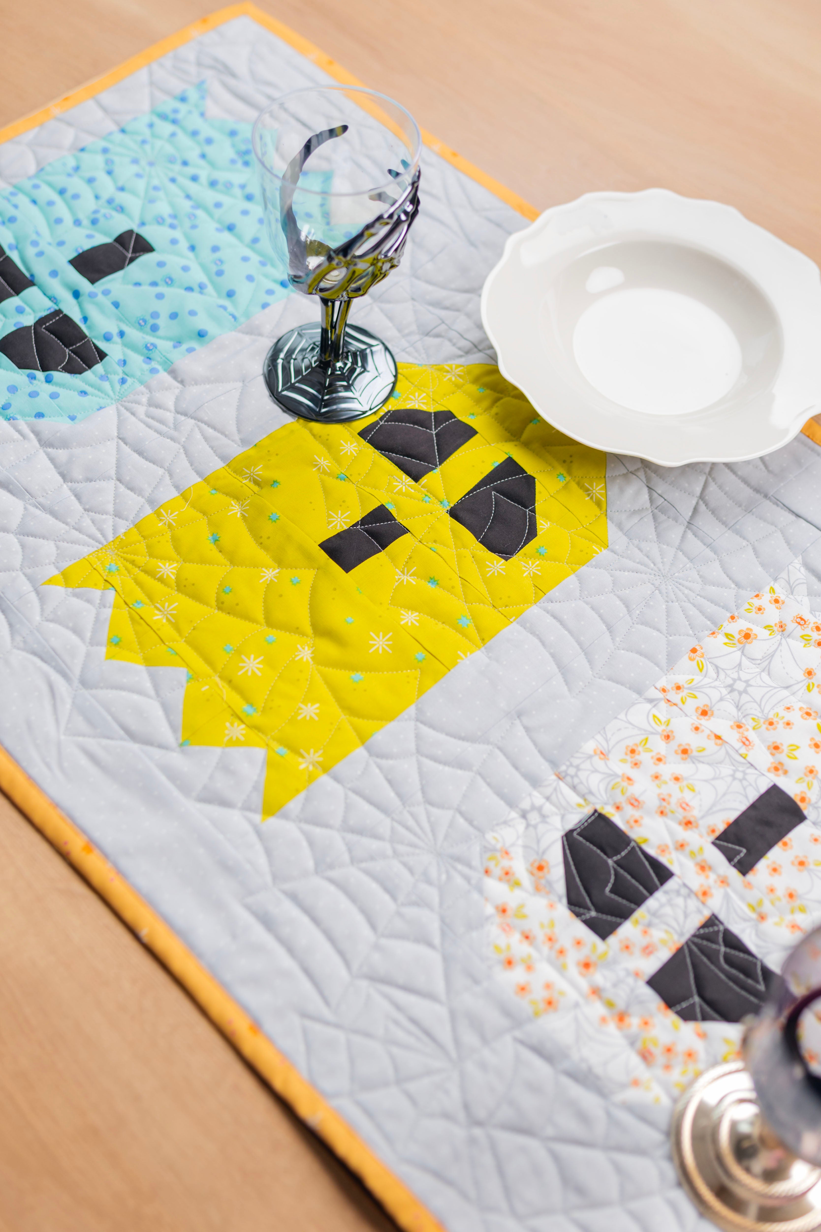 A close up of a table runner with ghosts that shows off the spider web quilting.