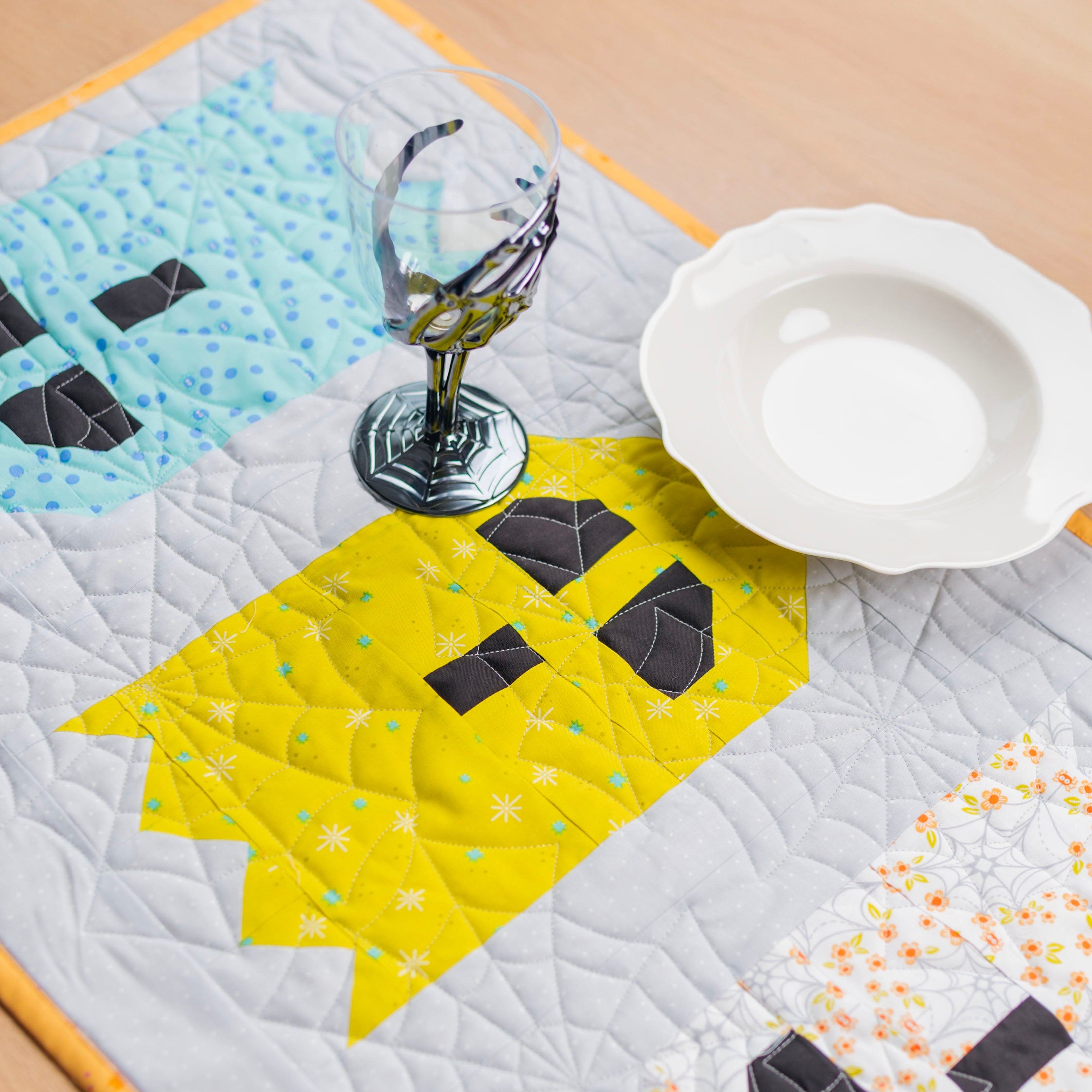 A close up of a table runner with ghosts that shows off the spider web quilting.