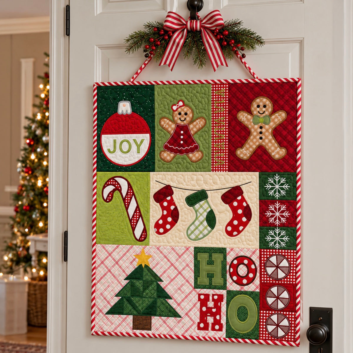 A square Christmas quilted wall hanging with a red-and-white striped ribbon loop and green pine garland at the top, displayed on a white door. The quilt features patchwork panels with gingerbread men, candy canes, stockings, snowflakes, a Christmas tree, and letters spelling HO, with a blurred lit Christmas tree in the background.