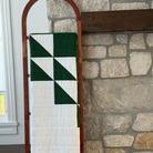 Quilt on a wooden ladder against a stone wall