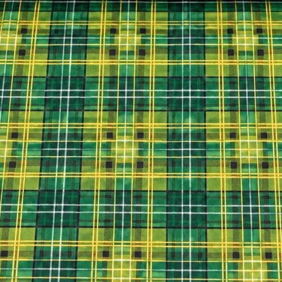 A close-up of a tartan plaid fabric pattern in green, yellow, and white, with small black square motifs at the intersections.