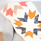 Colorful arrow-patterned quilt draped over a gray armchair.