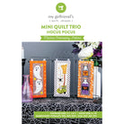Promotional graphic for a machine embroidery pattern titled 'Mini Quilt Trio Hocus Pocus' by my girlfriend's quilt shoppe, showing three Halloween-themed quilt panels displayed on a table with decorative vases and flowers.