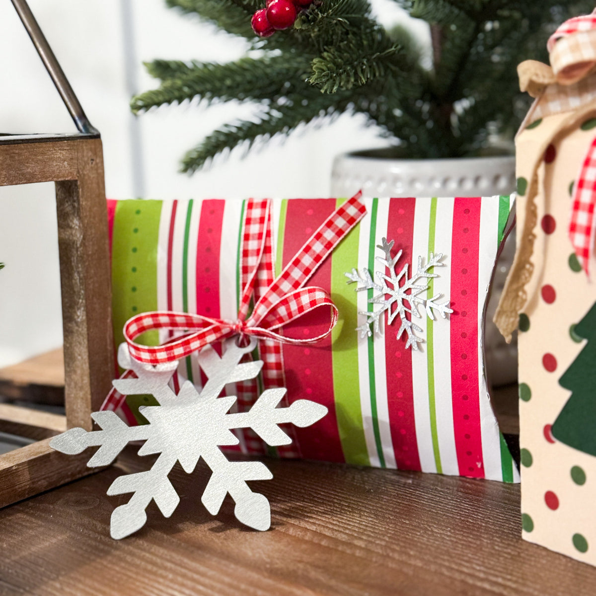 Christmas-themed gift with striped paper, red bow, and snowflake decorations on a wooden surface.