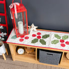 Decorative table with a quilt, red lantern, and clock against a dark wall.