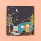 Quilted fabric panel with a camper, trees, and night sky design on a peach background