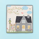 Children's quilt with a house, tree, and birds on a light blue background