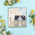 Decorative wall art of a house with flowers on a blue background