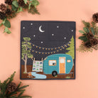 Patchwork quilt with a camper design surrounded by pinecones and greenery on a peach background
