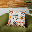 Decorative pillow with a geometric pattern on a green armchair against a wooden wall.