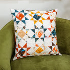 Patchwork pillow with multicolor patterns on a green armchair.