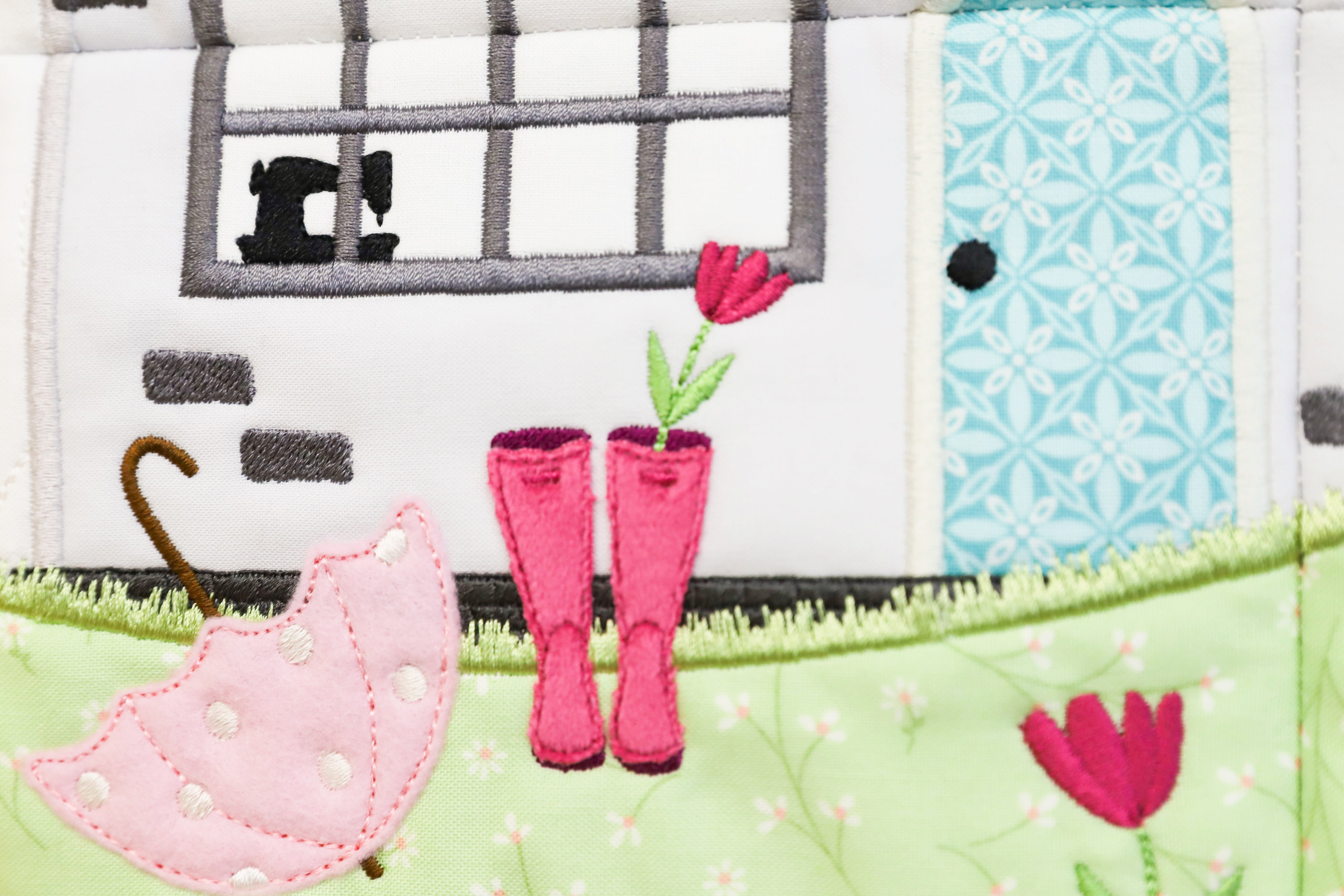 Patchwork quilt with pink boots, umbrella, and flowers