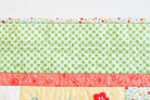 Quilt with green checkered pattern, red floral border, and yellow center on a white background