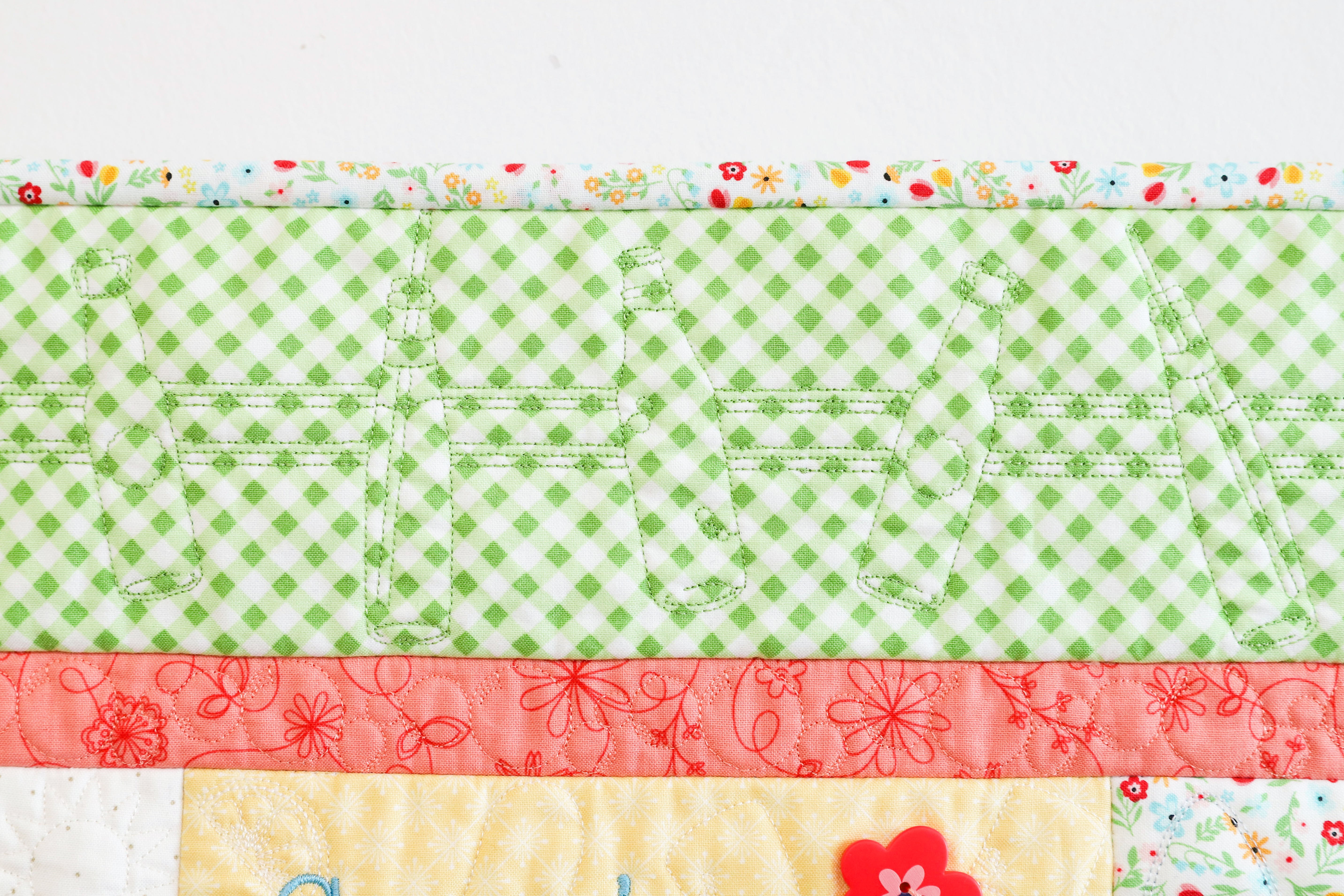 Quilt with green checkered pattern, red floral border, and yellow center on a white background