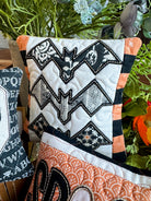 Decorative pillow with bat pattern and Halloween-themed design in a room setting.