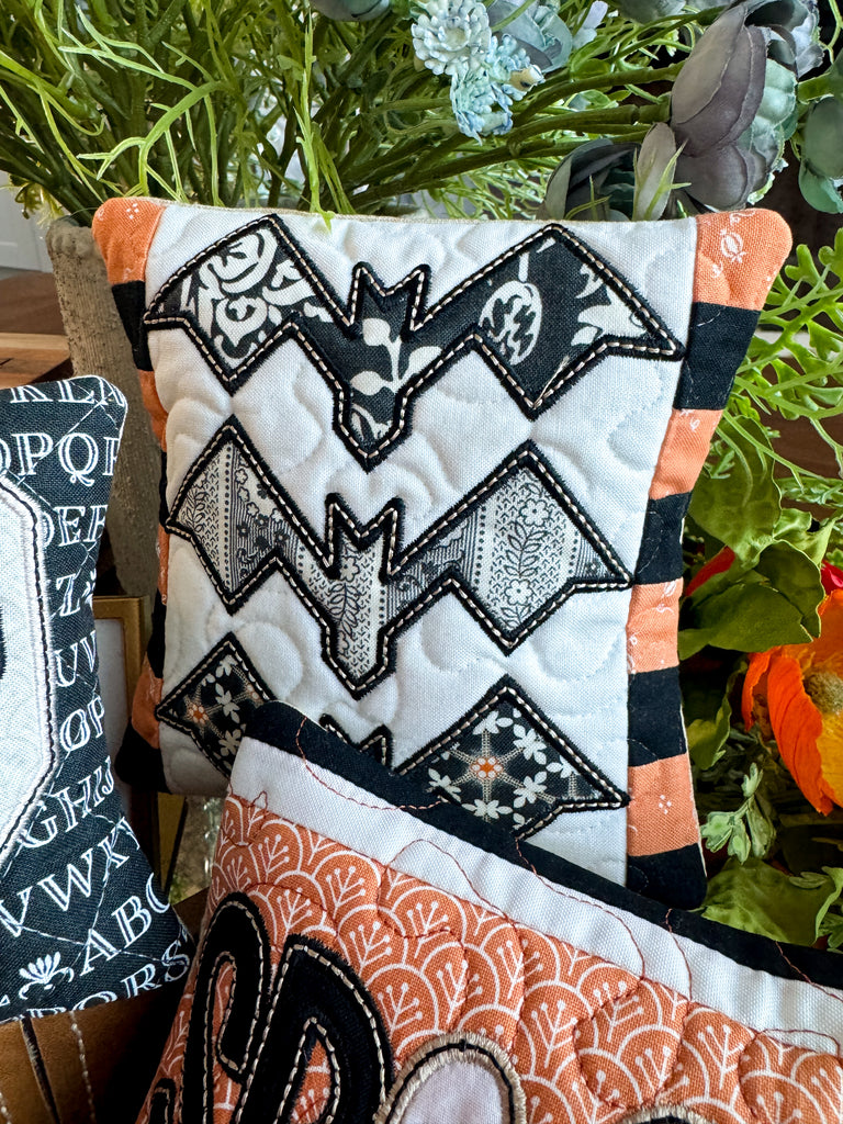Decorative pillow with bat pattern and Halloween-themed design in a room setting.