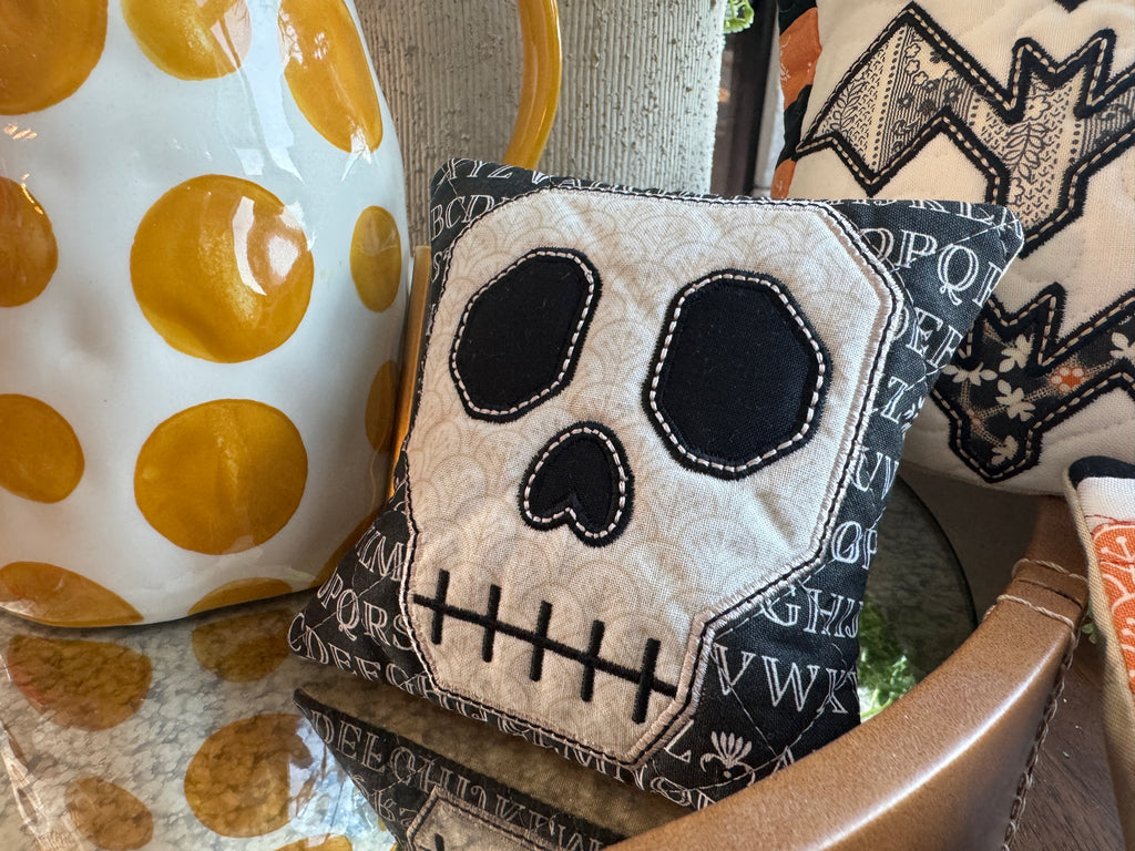 Decorative pillow with skull design on a chair next to a polka dot item.