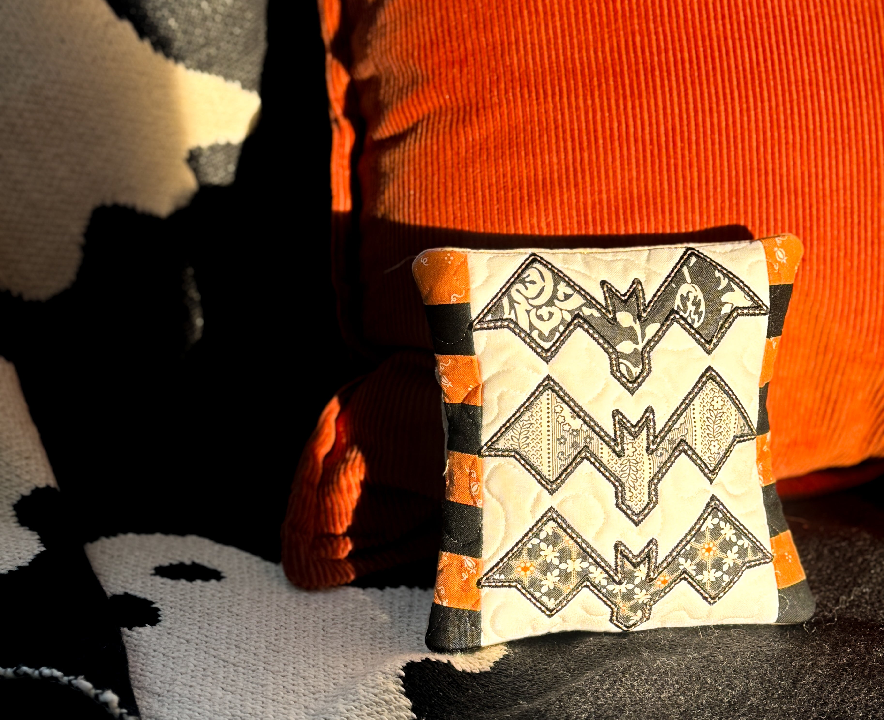 Decorative pillow with bat pattern on a black and orange background